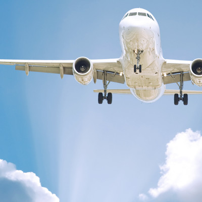 Airplane flying in blue sky with a few white clouds