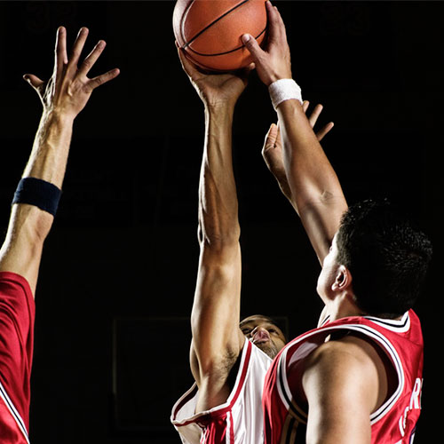 Image of 3 people disputing a basketball ball.